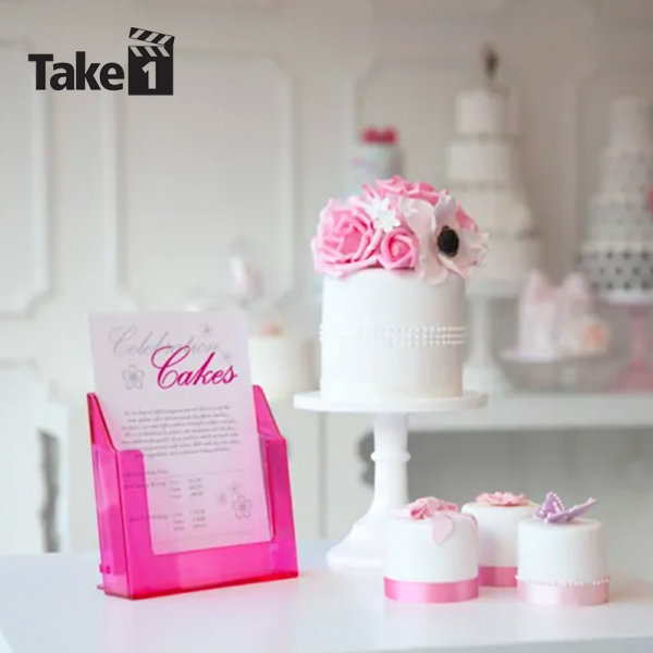 Pink tinted leaflet dispenser on a counter top next to a cake display